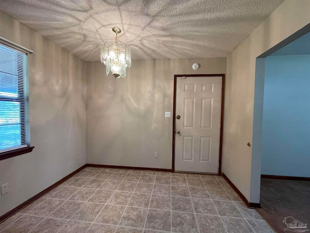 interior space with a notable chandelier, a textured ceiling, and a wealth of natural light