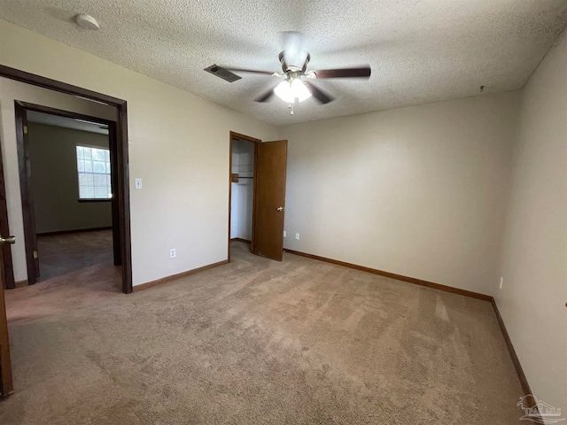 unfurnished bedroom with ceiling fan, carpet, and a textured ceiling