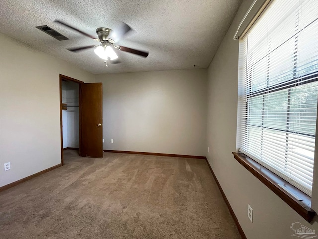 unfurnished bedroom with light carpet, a closet, a textured ceiling, and ceiling fan