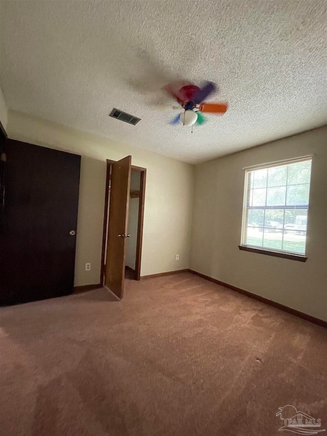 unfurnished bedroom featuring a textured ceiling, light colored carpet, and ceiling fan