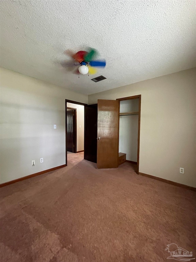 unfurnished bedroom with a textured ceiling, carpet floors, and ceiling fan