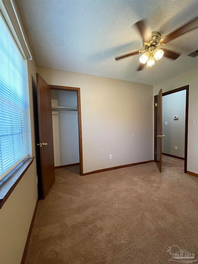 unfurnished bedroom with light carpet, a closet, a textured ceiling, and ceiling fan