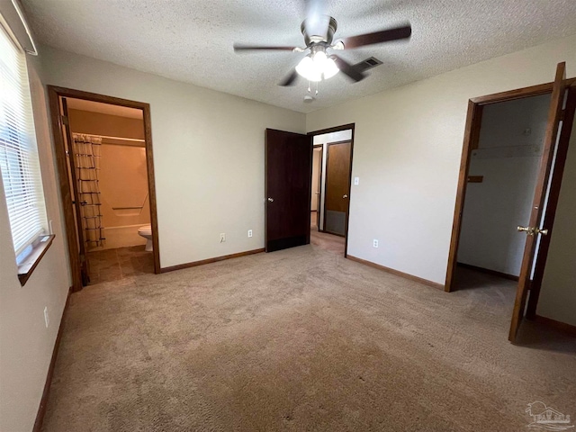 unfurnished bedroom featuring a closet, ceiling fan, a textured ceiling, and a walk in closet