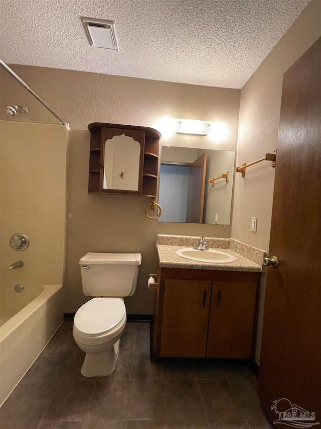 full bathroom with washtub / shower combination, a textured ceiling, toilet, vanity, and tile patterned flooring