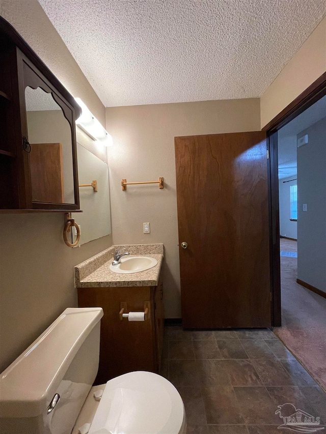 bathroom featuring vanity, a textured ceiling, and toilet