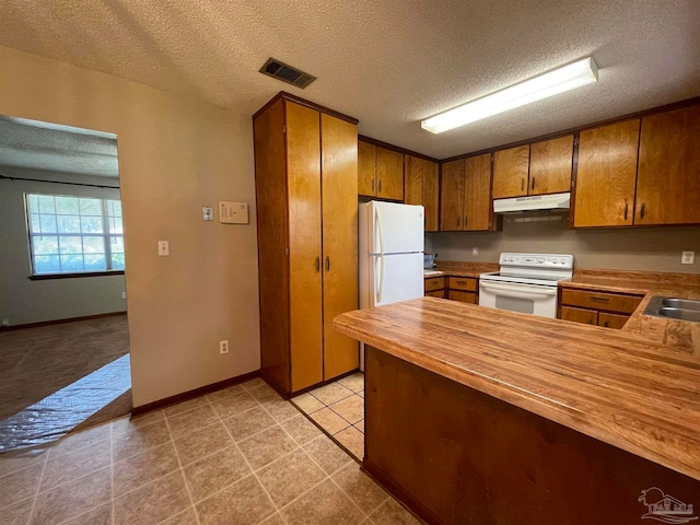 kitchen featuring a textured ceiling, butcher block countertops, and white appliances