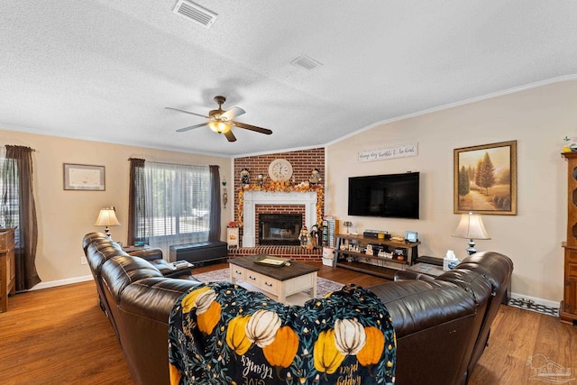 living room with a fireplace, crown molding, wood-type flooring, and a textured ceiling