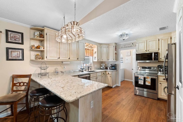 kitchen with kitchen peninsula, crown molding, pendant lighting, a breakfast bar, and appliances with stainless steel finishes