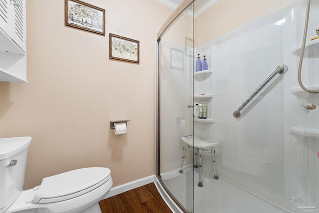 bathroom with hardwood / wood-style floors, toilet, walk in shower, and crown molding