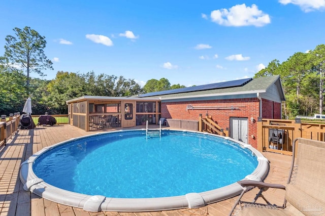 view of swimming pool featuring a sunroom and a deck