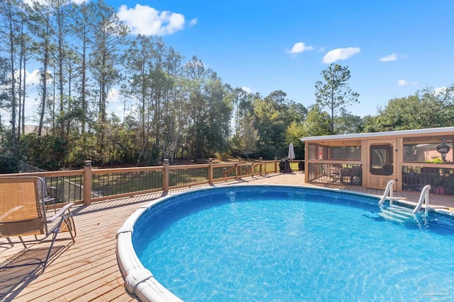 view of swimming pool with a wooden deck and a sunroom