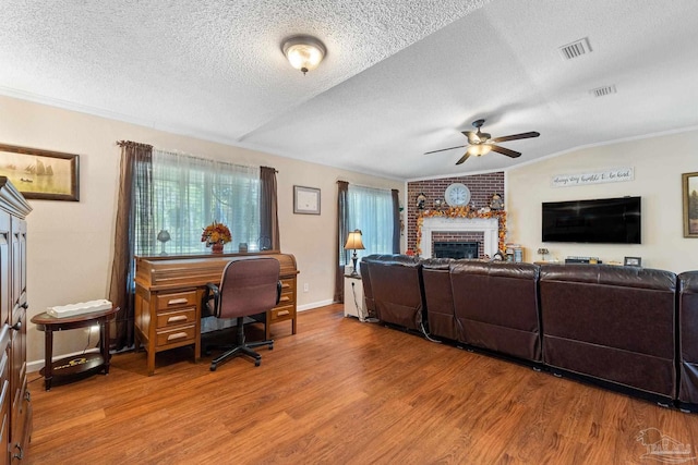 living room featuring lofted ceiling, ceiling fan, a fireplace, a textured ceiling, and wood-type flooring