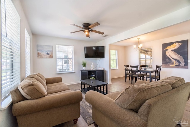 living room with ceiling fan with notable chandelier and hardwood / wood-style floors