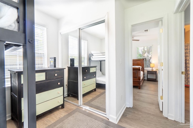 bedroom with multiple windows, light wood-type flooring, and a closet