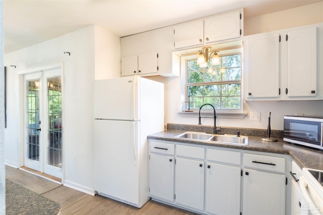 kitchen with light hardwood / wood-style flooring, white cabinets, sink, a chandelier, and white fridge