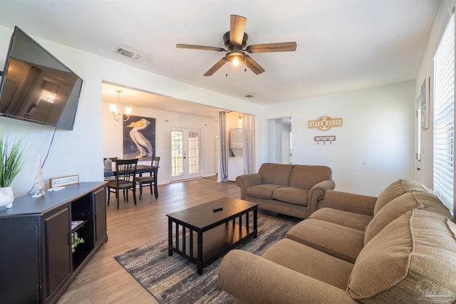 living room with ceiling fan with notable chandelier, french doors, and hardwood / wood-style floors