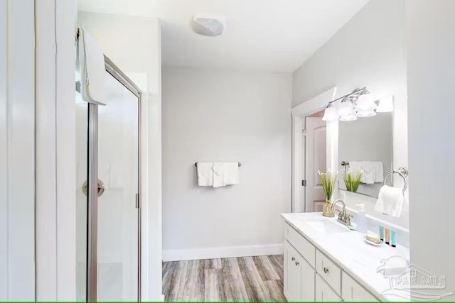 full bathroom featuring baseboards, wood finished floors, vanity, and a stall shower