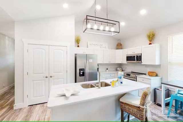 kitchen with a sink, light wood-style floors, white cabinetry, light countertops, and appliances with stainless steel finishes