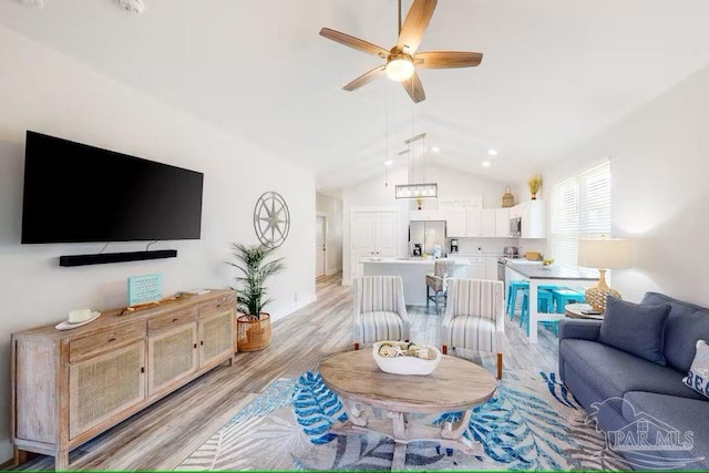 living room featuring vaulted ceiling, light wood-style flooring, and ceiling fan
