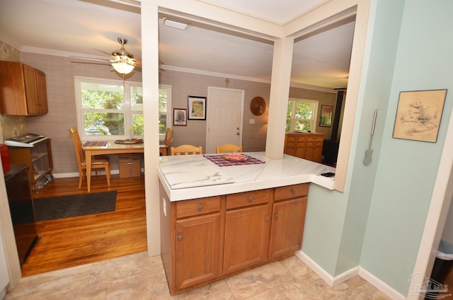 2153 Bergren Rd, Gulf Breeze, FL 32563 - kitchen with ornamental molding, light countertops, ceiling fan, brown cabinets, and a peninsula