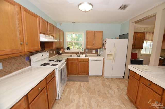 2153 Bergren Rd, Gulf Breeze, FL 32563 - kitchen with white appliances, under cabinet range hood, decorative backsplash, light countertops, and brown cabinets