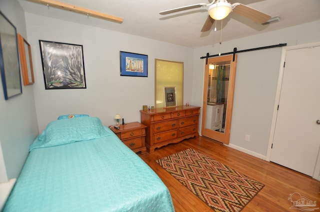 2153 Bergren Rd, Gulf Breeze, FL 32563 - bedroom featuring a barn door, wood finished floors, a ceiling fan, and ensuite bathroom
