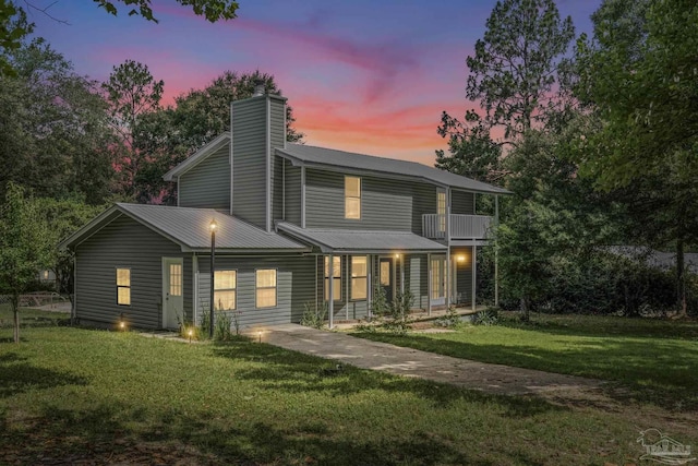 6136 Beasley Rd, Crestview, FL 32536 - back of house at dusk with a balcony, a chimney, a yard, and a metal roof