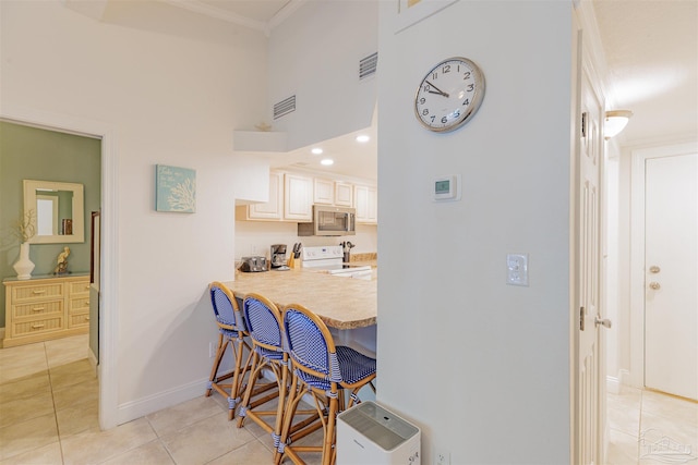 kitchen with light tile patterned floors, kitchen peninsula, a kitchen breakfast bar, ornamental molding, and white electric stove