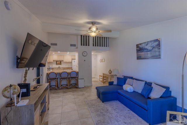 tiled living room featuring ceiling fan, a high ceiling, and ornamental molding