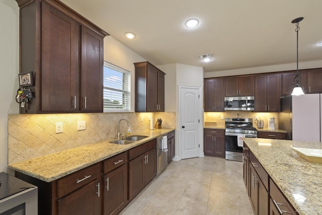 kitchen featuring sink, backsplash, hanging light fixtures, light stone counters, and stainless steel appliances