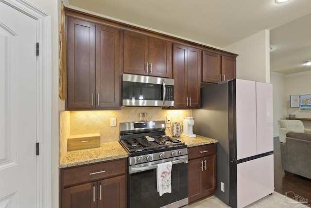 kitchen with stainless steel appliances, tasteful backsplash, dark brown cabinets, and light stone counters