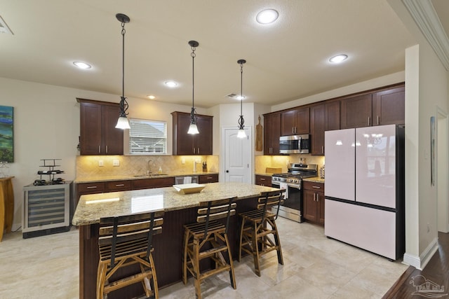 kitchen featuring sink, appliances with stainless steel finishes, hanging light fixtures, a center island, and light stone counters