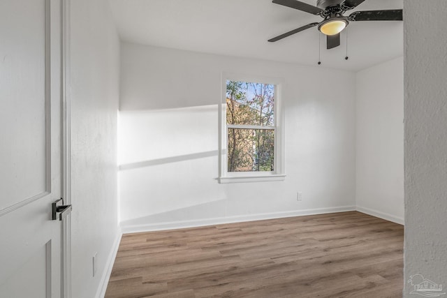 empty room featuring baseboards, wood finished floors, and ceiling fan