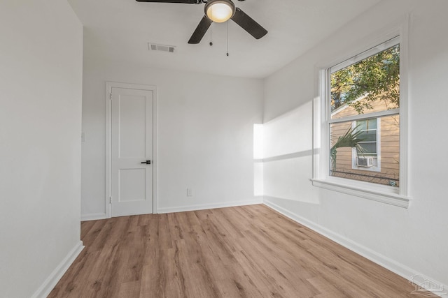 empty room featuring baseboards, wood finished floors, visible vents, and ceiling fan