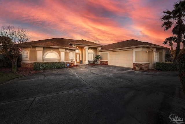 mediterranean / spanish home featuring a garage, stone siding, concrete driveway, and stucco siding