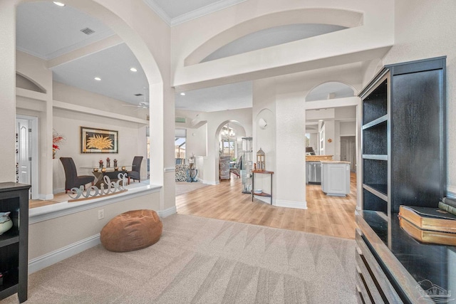 entryway featuring light carpet, light wood-type flooring, visible vents, and crown molding