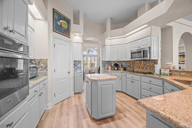 kitchen featuring light wood-type flooring, tasteful backsplash, appliances with stainless steel finishes, and white cabinets