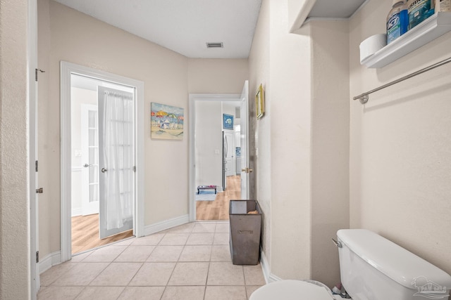 half bath featuring visible vents, tile patterned flooring, toilet, and baseboards