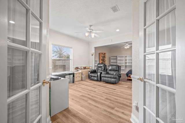 home office featuring light wood-type flooring, crown molding, visible vents, and a textured ceiling