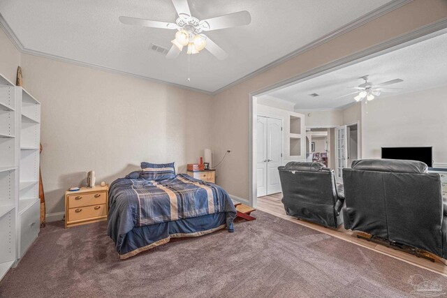 carpeted bedroom with visible vents, crown molding, a textured ceiling, and ceiling fan