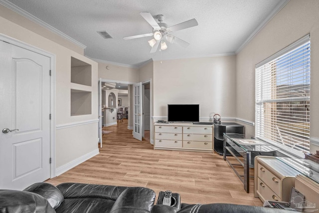 living area featuring visible vents, arched walkways, a textured ceiling, crown molding, and light wood-style floors