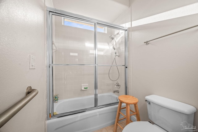 full bathroom featuring a textured wall, bath / shower combo with glass door, and toilet