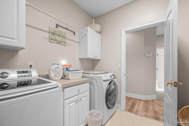 washroom featuring light tile patterned floors, washing machine and dryer, cabinet space, and baseboards