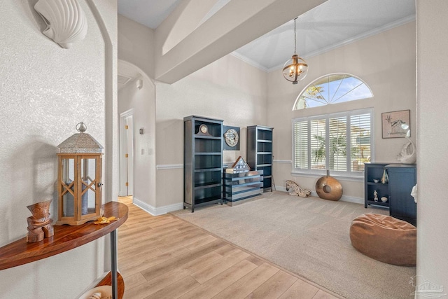 interior space featuring a notable chandelier, wood finished floors, a towering ceiling, baseboards, and ornamental molding