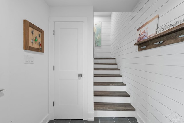 stairs featuring wood walls and tile patterned floors