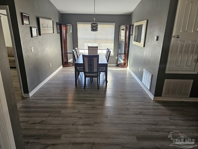 dining area with dark wood-type flooring, visible vents, and baseboards