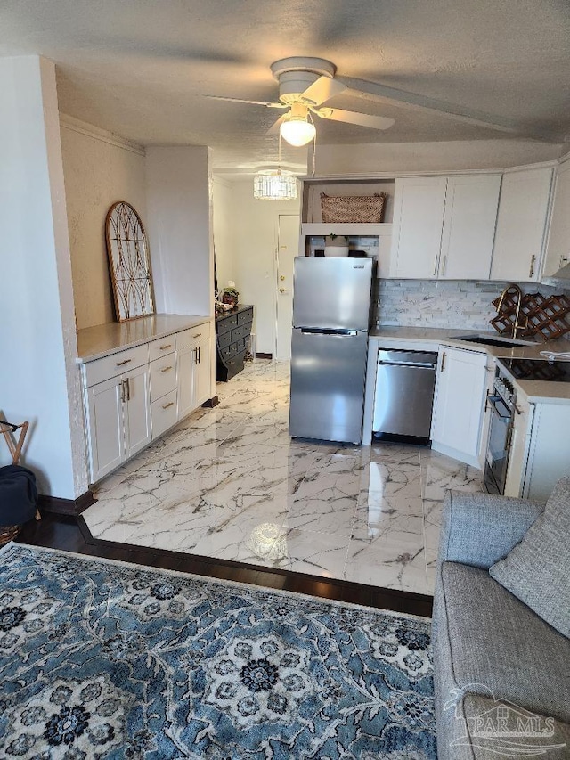 kitchen with sink, ceiling fan, appliances with stainless steel finishes, tasteful backsplash, and white cabinetry