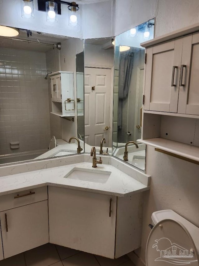 bathroom with toilet, vanity, and tile patterned floors