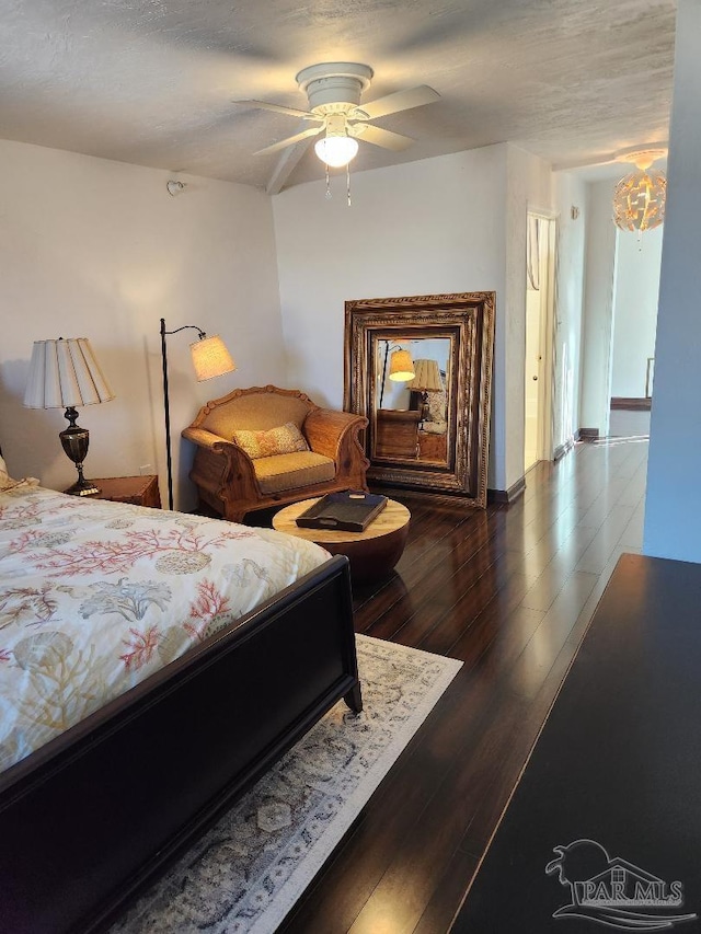 bedroom featuring ceiling fan with notable chandelier and dark hardwood / wood-style flooring