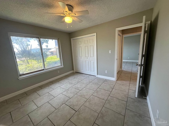 unfurnished bedroom featuring light tile patterned floors, a textured ceiling, ceiling fan, and a closet